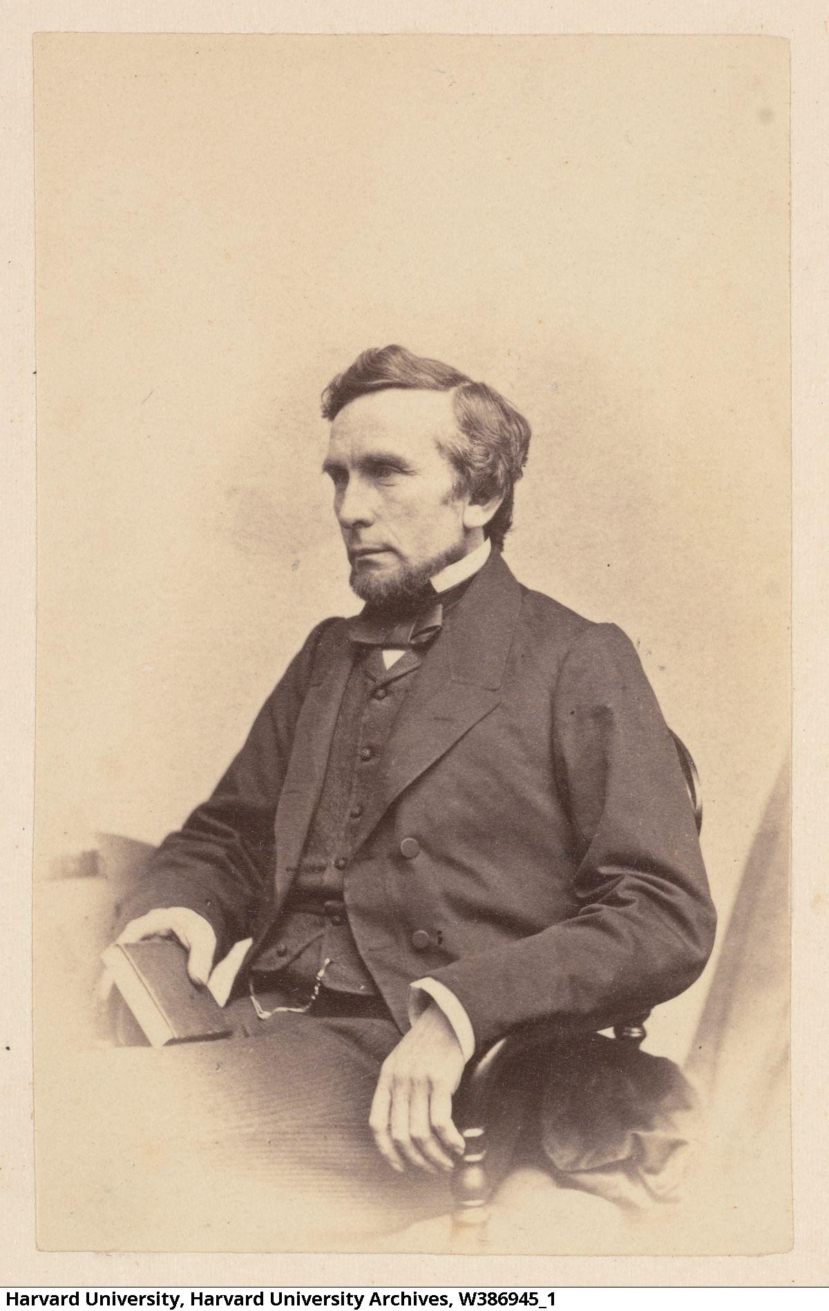 A photograph of Edward H. Clarke. He sits in a chair, holding a book. 