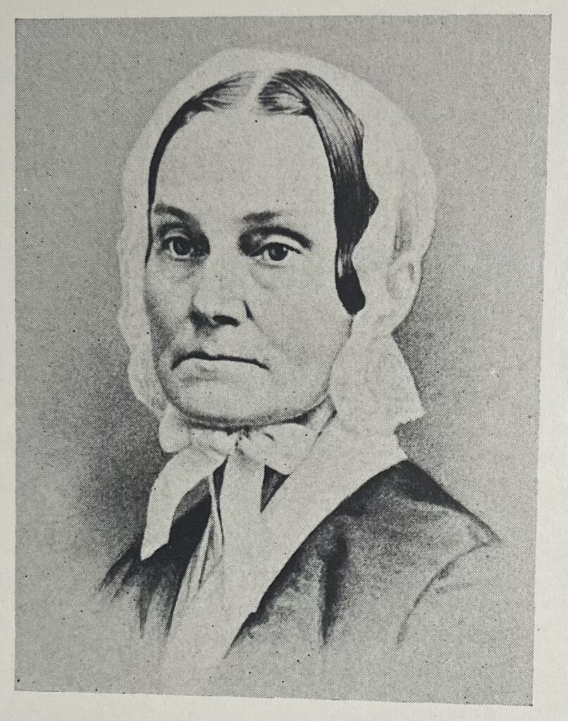A black and white photograph of Hannah Taylor wearing a simple bonnet and an unsmiling expression
